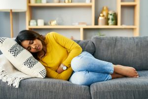 Woman laying on couch with her arms wrapped around her midsection