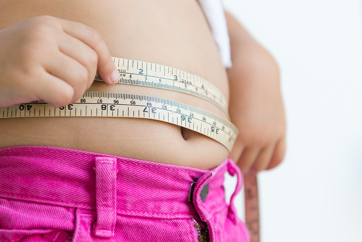 Girl measuring her belly with a tape measure
