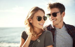 Couple in sunglasses smiling in bright sunlight on the beach