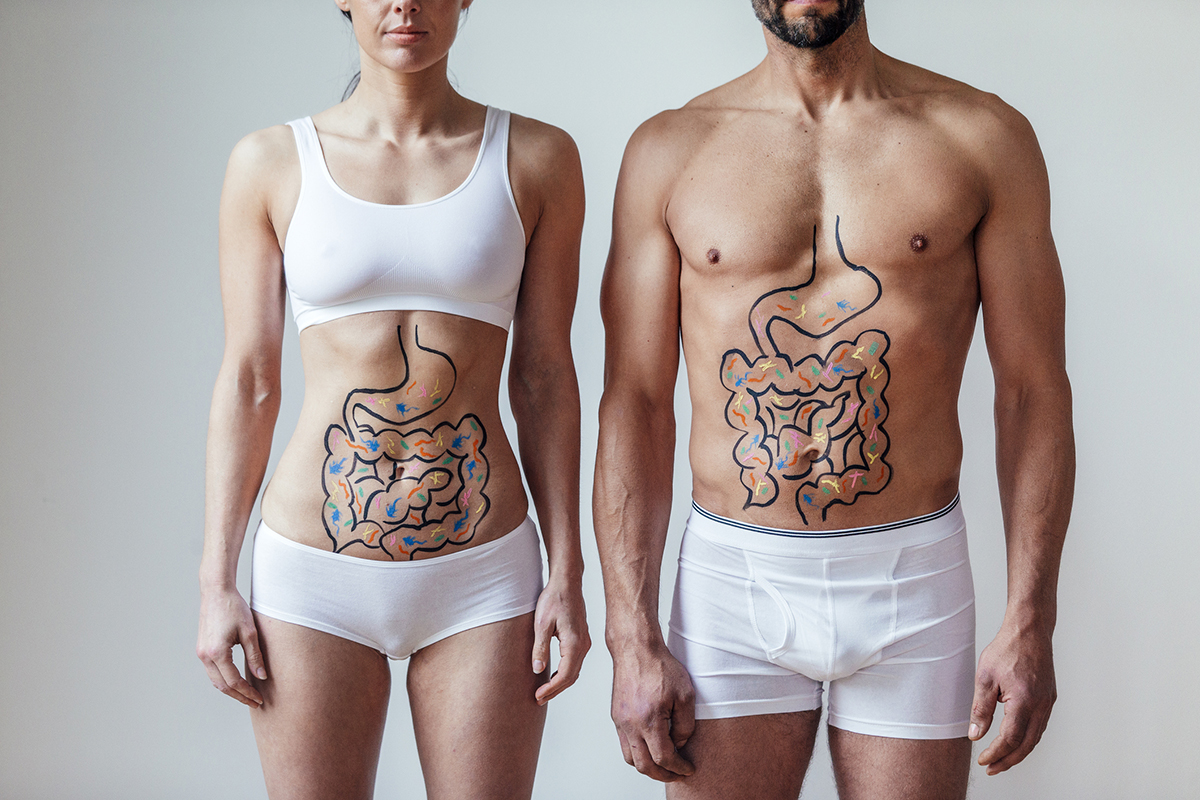 Man and woman standing side by side in white underwear. Their digestive tracts are drawn on their stomachs.