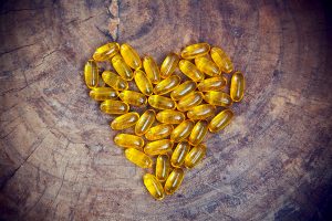 A heart shape made out of fish oil pills on a wooden background