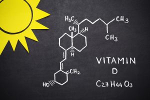Vitamin D molecular formaula drawn in chalk on a chalkboard background. Drawing of a sun in the top left corner.