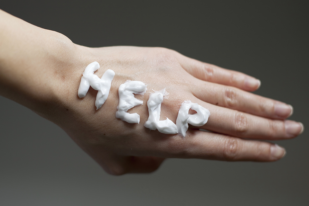 Hand with "help" written in lotion