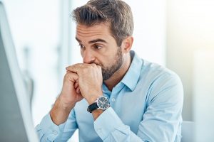 Man in business attire looking anxious at his desk