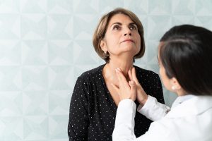 Woman having her thyroid examined by a doctor