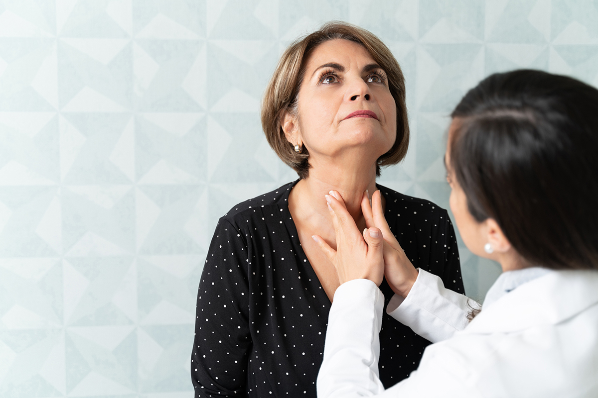 Woman having her thyroid examined by a doctor