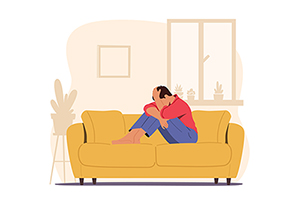 Illustration of depressed person on a yellow couch with their head in their hands