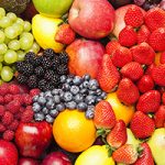 Close up on a fruit medley that includes strawberries, raspberries, blackberries, blueberries, apples, citrus fruits and grapes