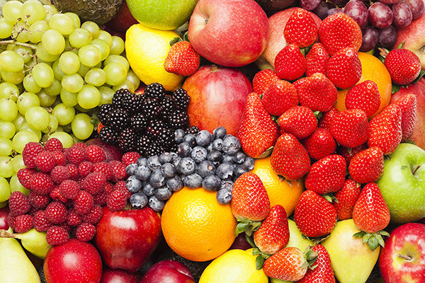 Close up on a fruit medley that includes strawberries, raspberries, blackberries, blueberries, apples, citrus fruits and grapes