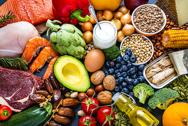 Overhead view of a large group of healthy raw food for flexitarian mediterranean diet. The composition includes salmon, chicken breast, canned tuna, cow steak, fruits, vegetables, nuts, seeds, dairi products, olive oil, eggs and legumes.