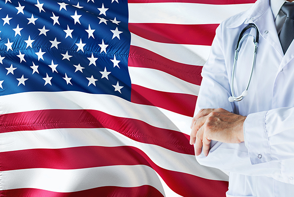 Doctor standing with stethoscope on United States flag background.