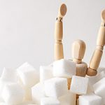 Anatomical model with arms up sinking into a pile of sugar cubes