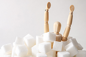 Anatomical model with arms up sinking into a pile of sugar cubes