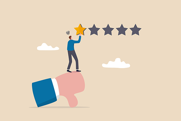 Illustration of a one-star review, with a man standing on a thumb that's pointing downward in order to hang one yellow star next to four empty ones