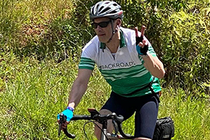 Dr. Ronald Hoffman giving a peace sign while cycling in Costa Rica.
