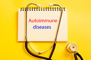 Yellow background with a spiral notepad that reads "autoimmune diseases" in typed letters. A stethoscope is draped over top.