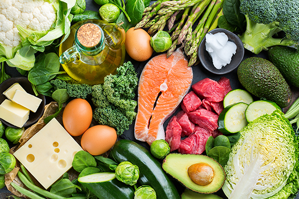 Balanced diet nutrition keto concept. Assortment of healthy ketogenic low carb food ingredients for cooking on a kitchen table. Green vegetables, meat, salmon, cheese, eggs.