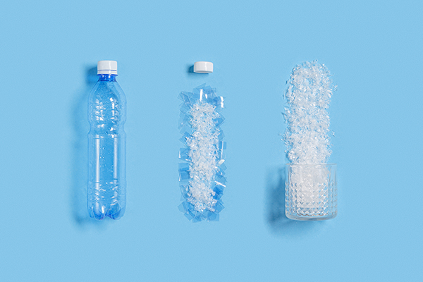 Three plastic water bottles in increasing stages of breakdown, representing the proliferation of microplastic pollution.