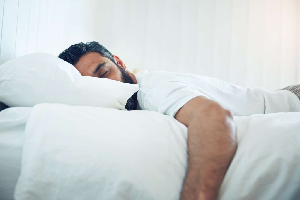 Man asleep in bed on his stomach