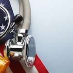 A prescription medication bottle and a stethoscope rest on top of an American flag.