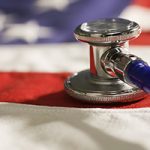 Social and political issue of healthcare and medicine changes and reform in USA politics and policies, symbolized by a close-up of a stethoscope resting on a the cloth fabric of the United States flag.