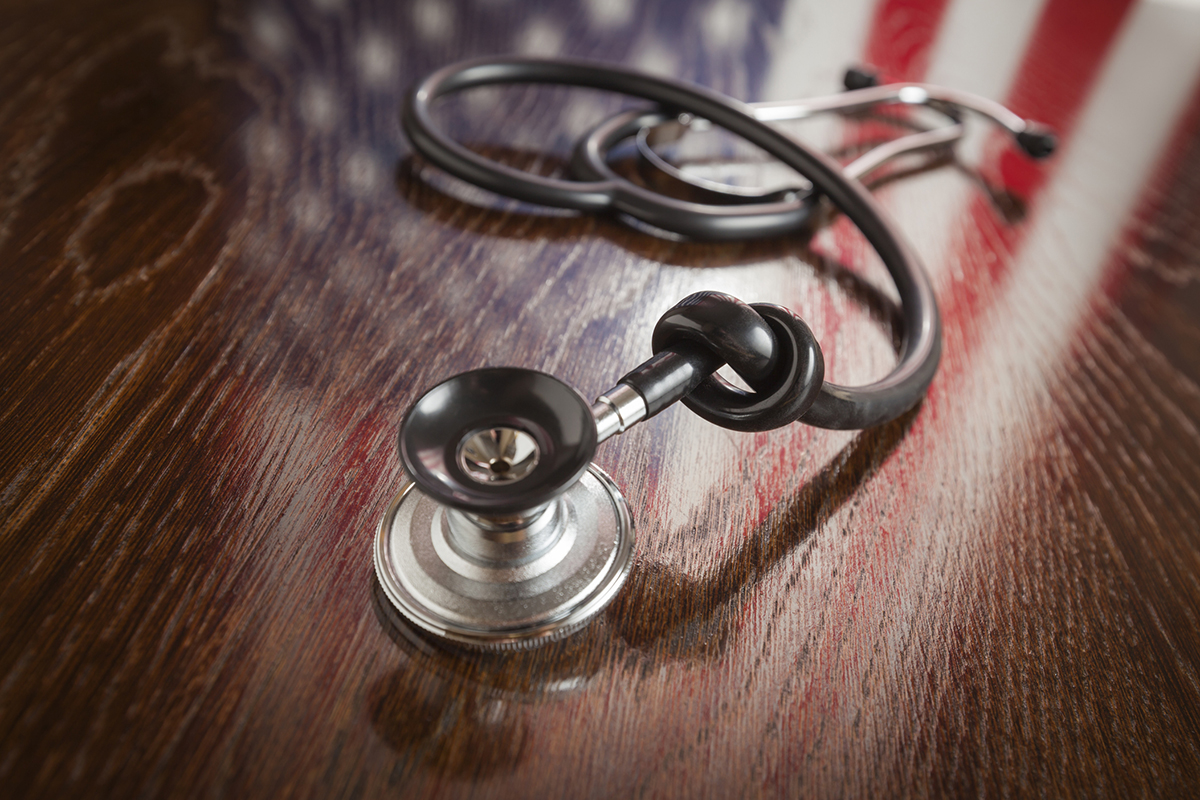 Knotted Stethoscope with American Flag Reflection on Wooden Table.