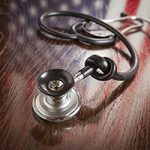 Knotted Stethoscope with American Flag Reflection on Wooden Table.