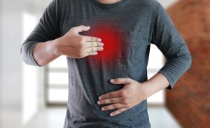 Man rubbing his stomach and chest with a red glow beneath his hand
