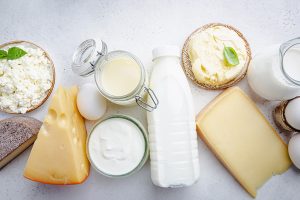 Fresh dairy products, milk, cottage cheese, eggs, yogurt, sour cream and butter on white table, top view