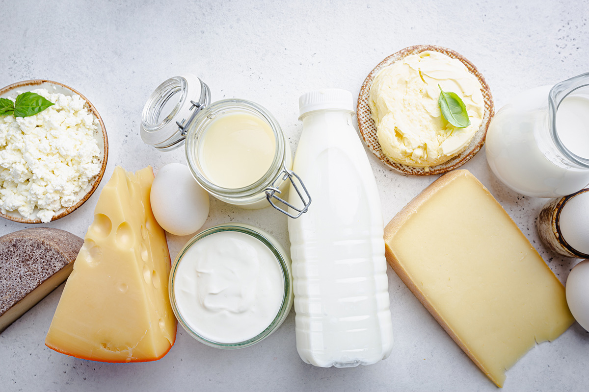 Fresh dairy products, milk, cottage cheese, eggs, yogurt, sour cream and butter on white table, top view