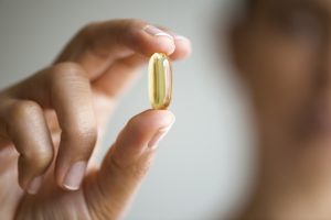 Woman holding omega 3 capsule.