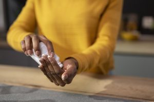 Close up of woman in a yellow sweater pouring supplements from a pill bottle into her hand.