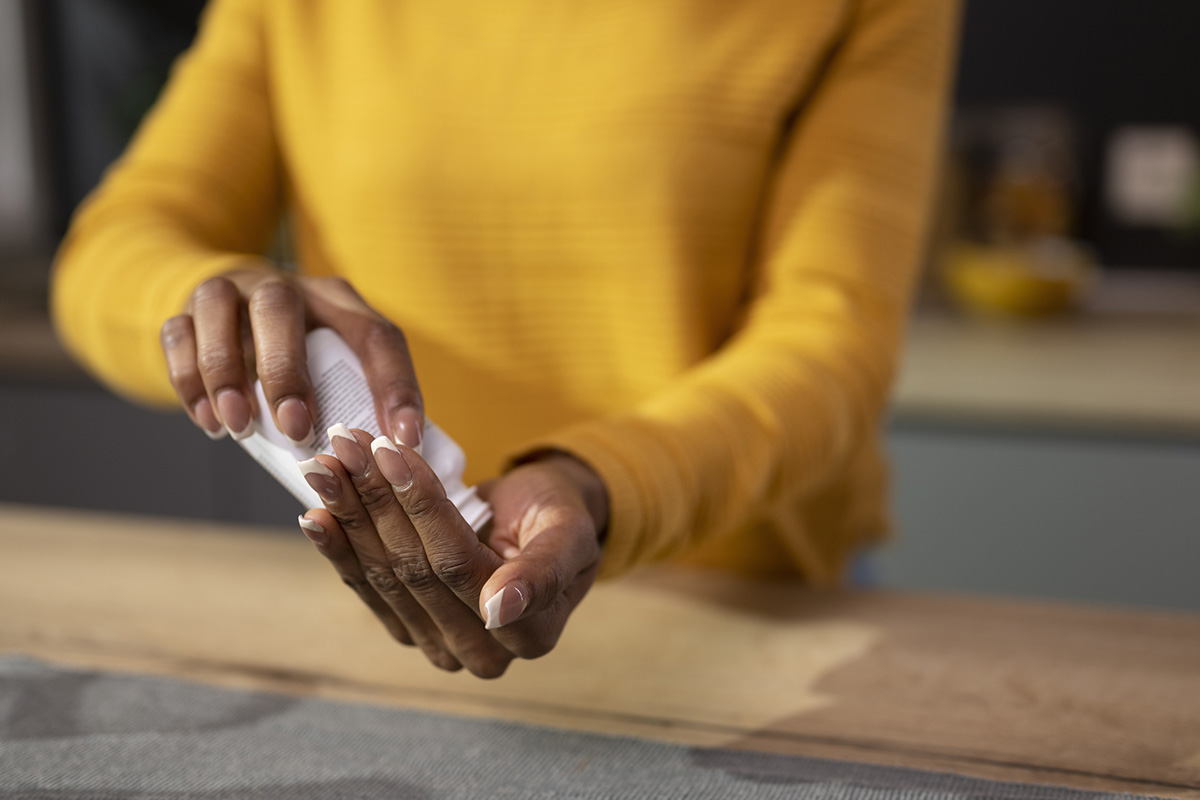 Close up of woman in a yellow sweater pouring supplements from a pill bottle into her hand.