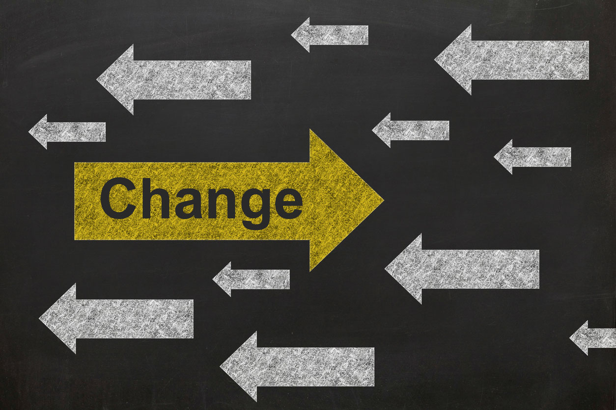 Blackboard illustration with many white arrows pointing to the left and a single yellow arrow pointing to the right with the word "change" written inside.
