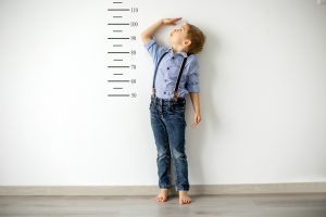 Young boy measuring his height against the wall