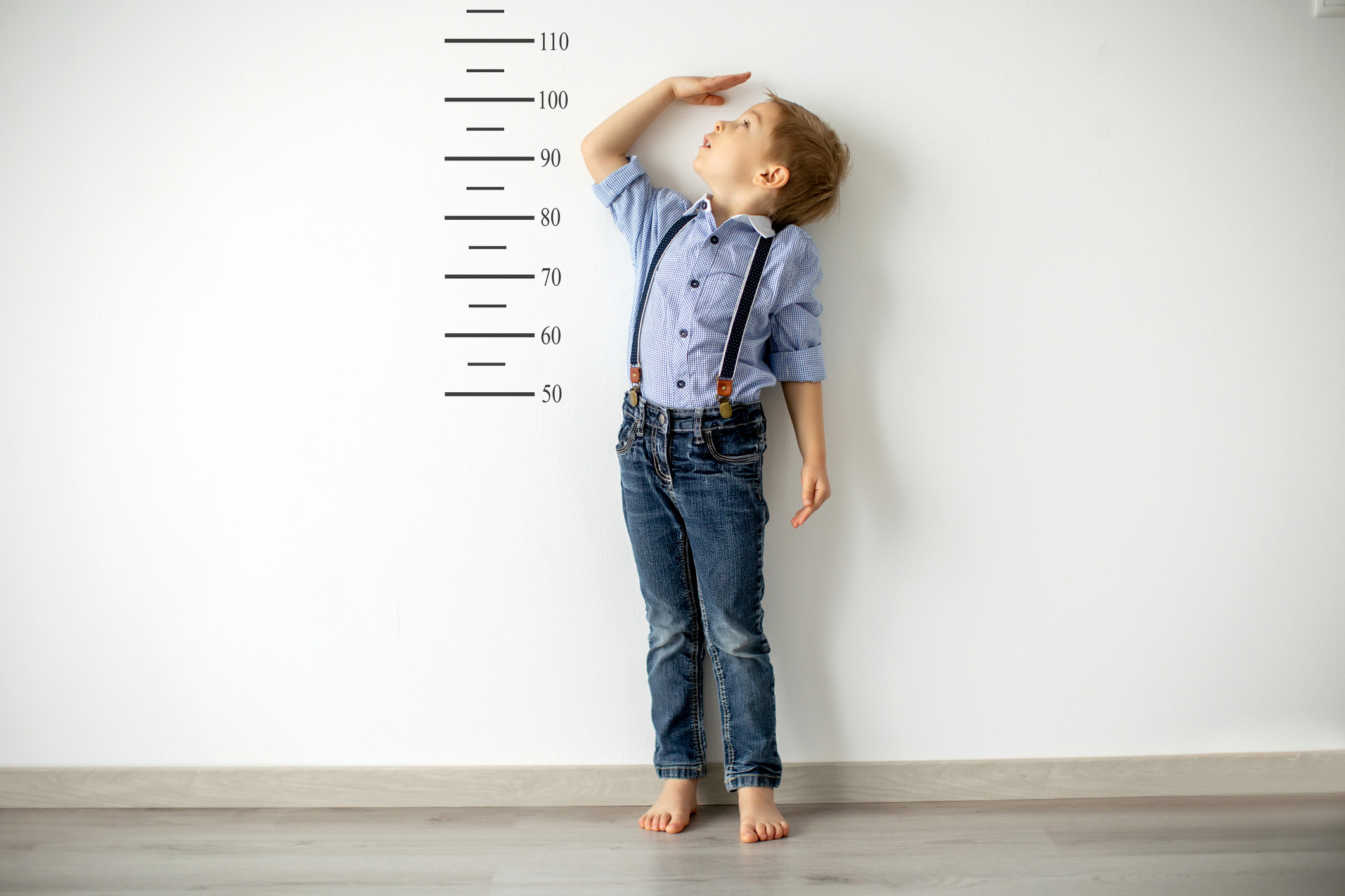 Young boy measuring his height against the wall