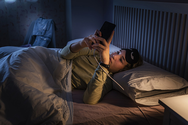 Teenage girl using smartphone in bed at night