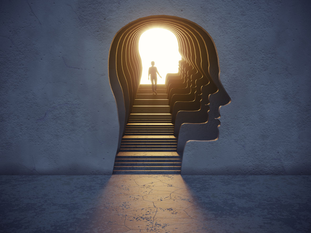 Person standing a the top of a stairwell that extends into a head-shaped hole in the wall