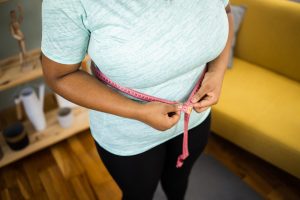 Young woman measuring waist with measuring tape
