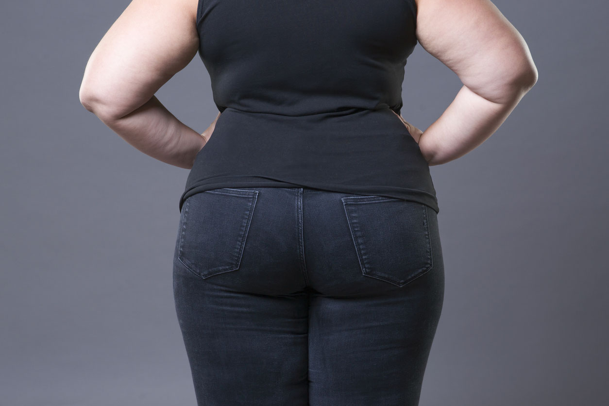 Plus size caucasian woman in a black t-shirt and blue jeans, viewed from behind with her hands on her hips
