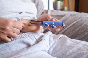 Woman injecting a syringe of semaglutide into her belly.