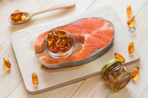 Vitamin D source from fish oil capsules and salmon on wooden background