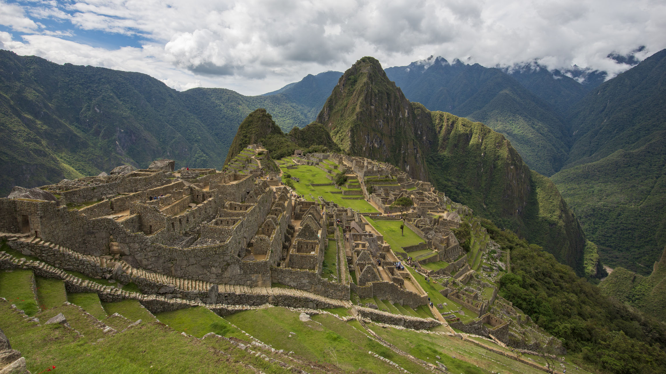 15th Century Inca Citadel of Machu Picchu in Peru, viewed here on a cloudy day with mountains in the background and ancient ruins on the landscape.