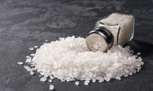 Pile of salt and salt shaker on black table