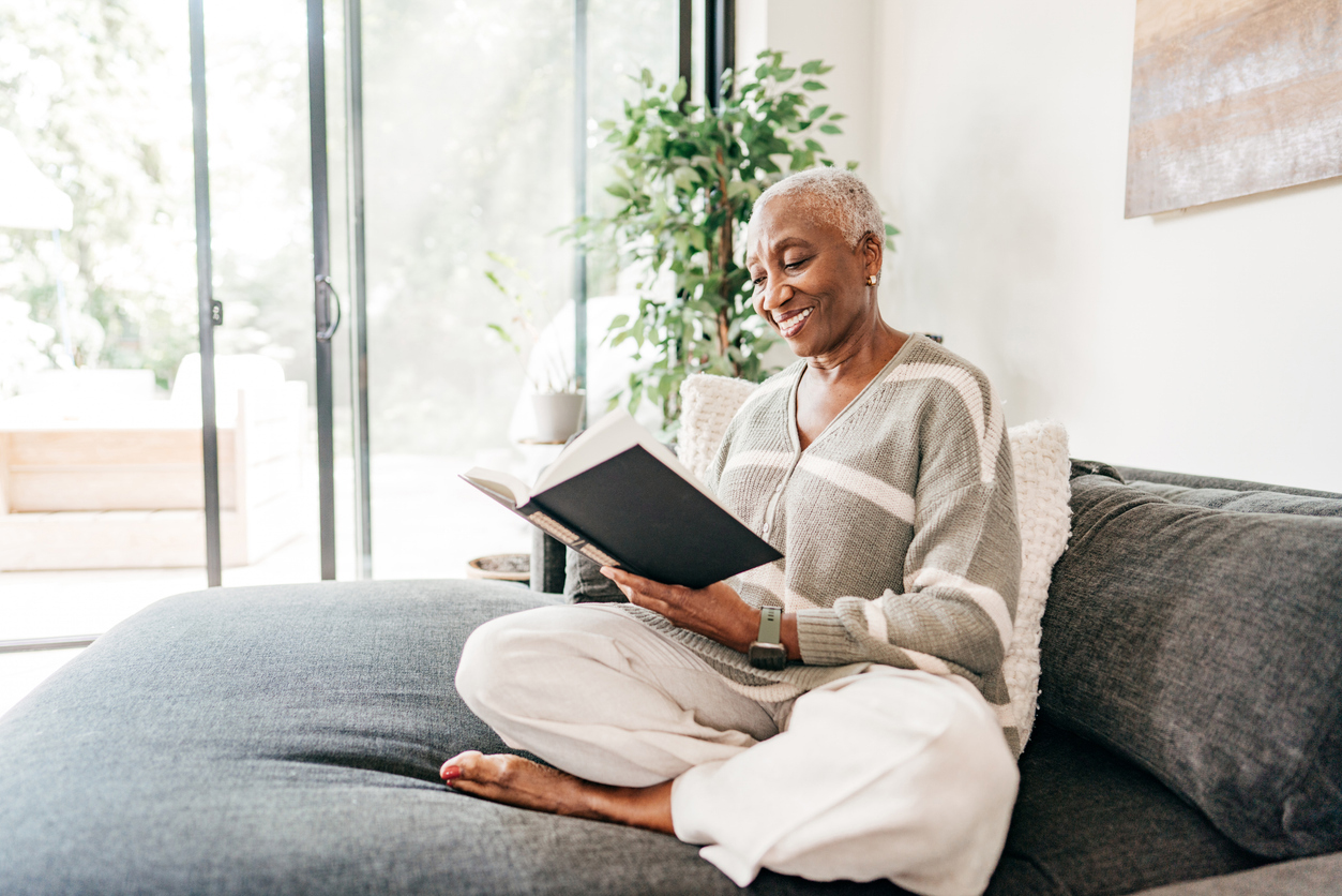 Senior women sitting on sofa and reading a book at home